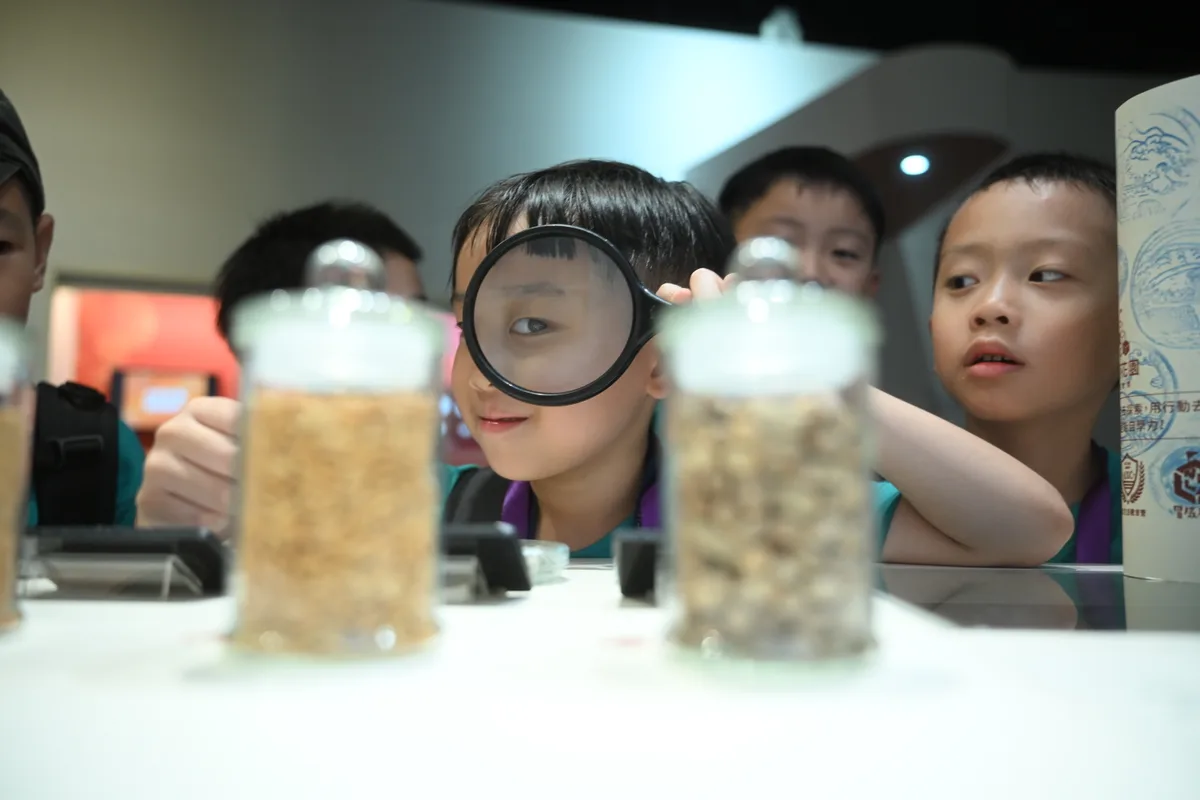 孩子拿著放大鏡觀察展示瓶