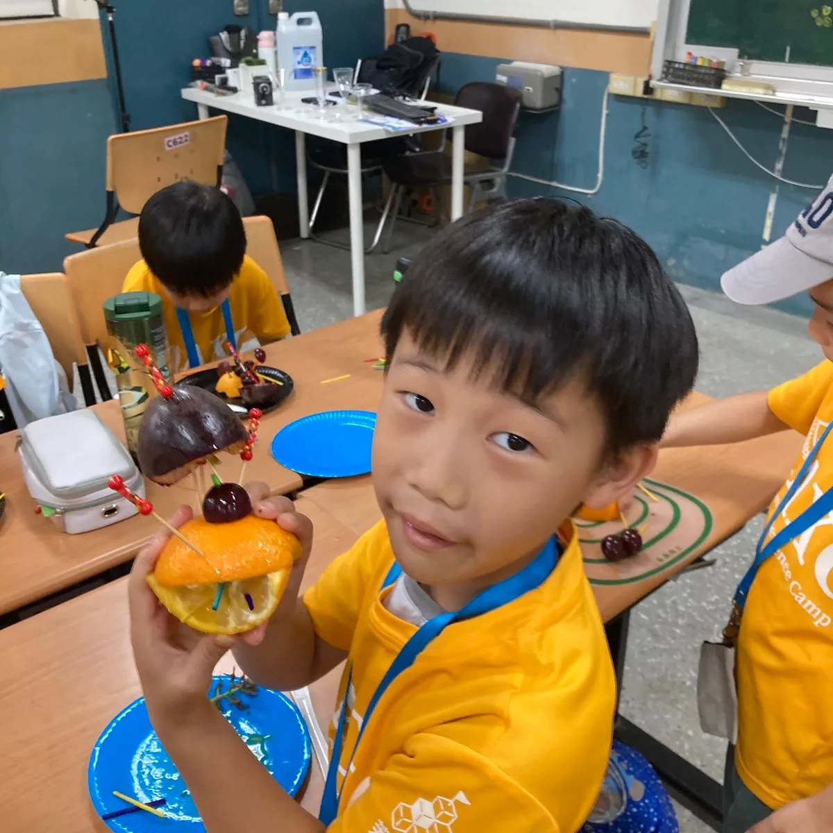 男孩舉起自己用水果與竹籤組成的作品給鏡頭看