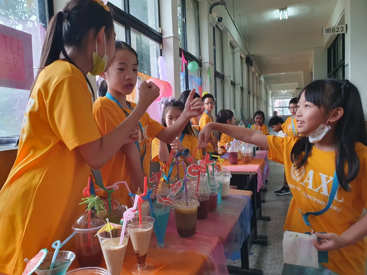 走廊上孩子擺的飲料攤，櫃台後的孩子正跟客人比手勢談價錢