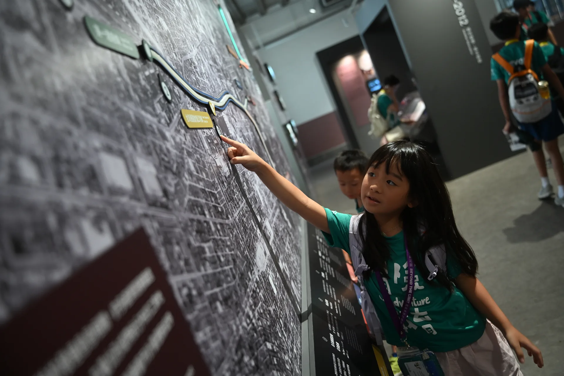 孩子背著背包，指著城市地圖確認位置