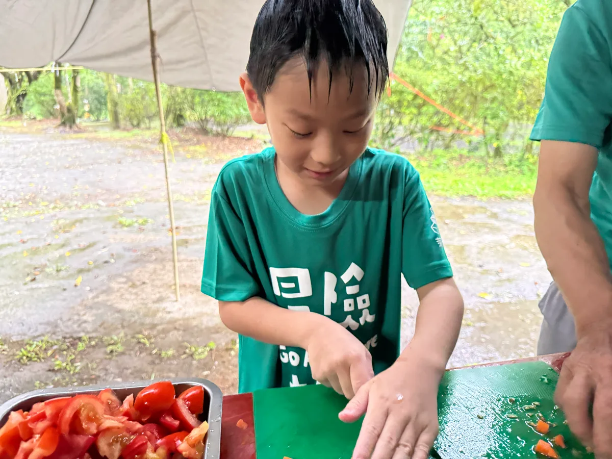 孩子在砧板上切食材，旁邊有一盤番茄