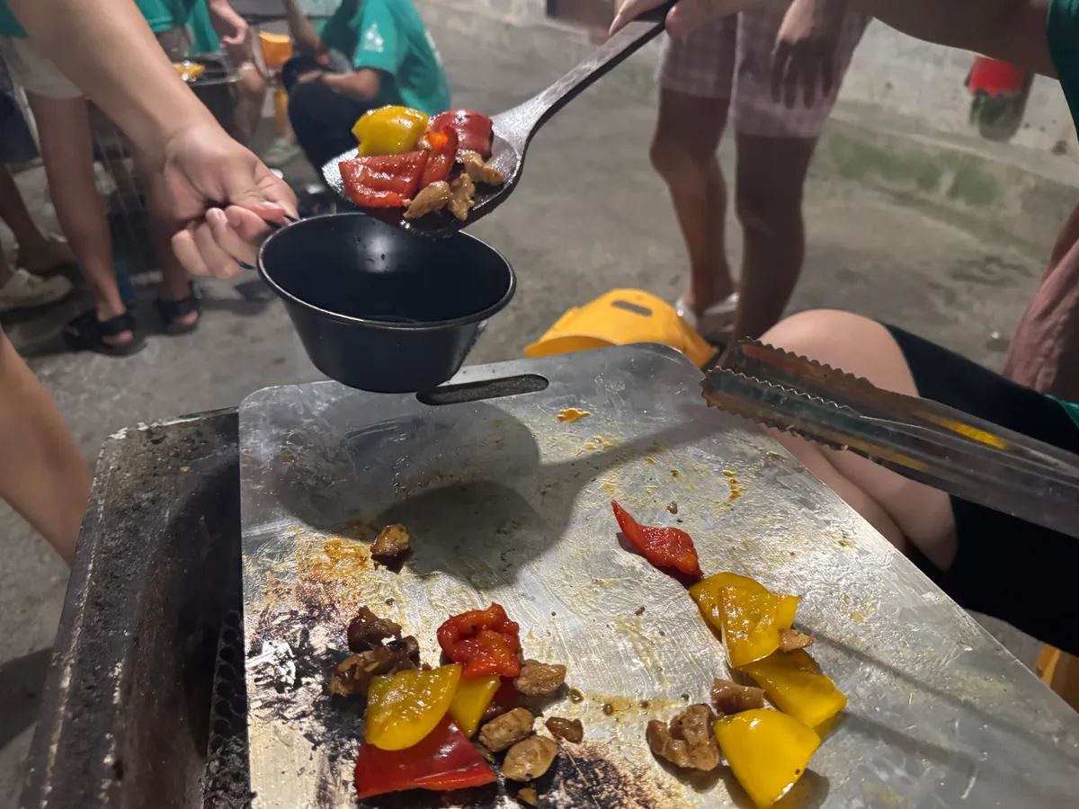 鍋鏟將蔬菜和肉盛向手持的碗中