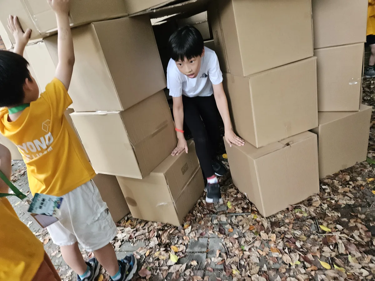 孩子從自己用紙箱搭建的堡壘結構中鑽出